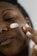 Close-up of hands applying cream on smooth skin in natural light.