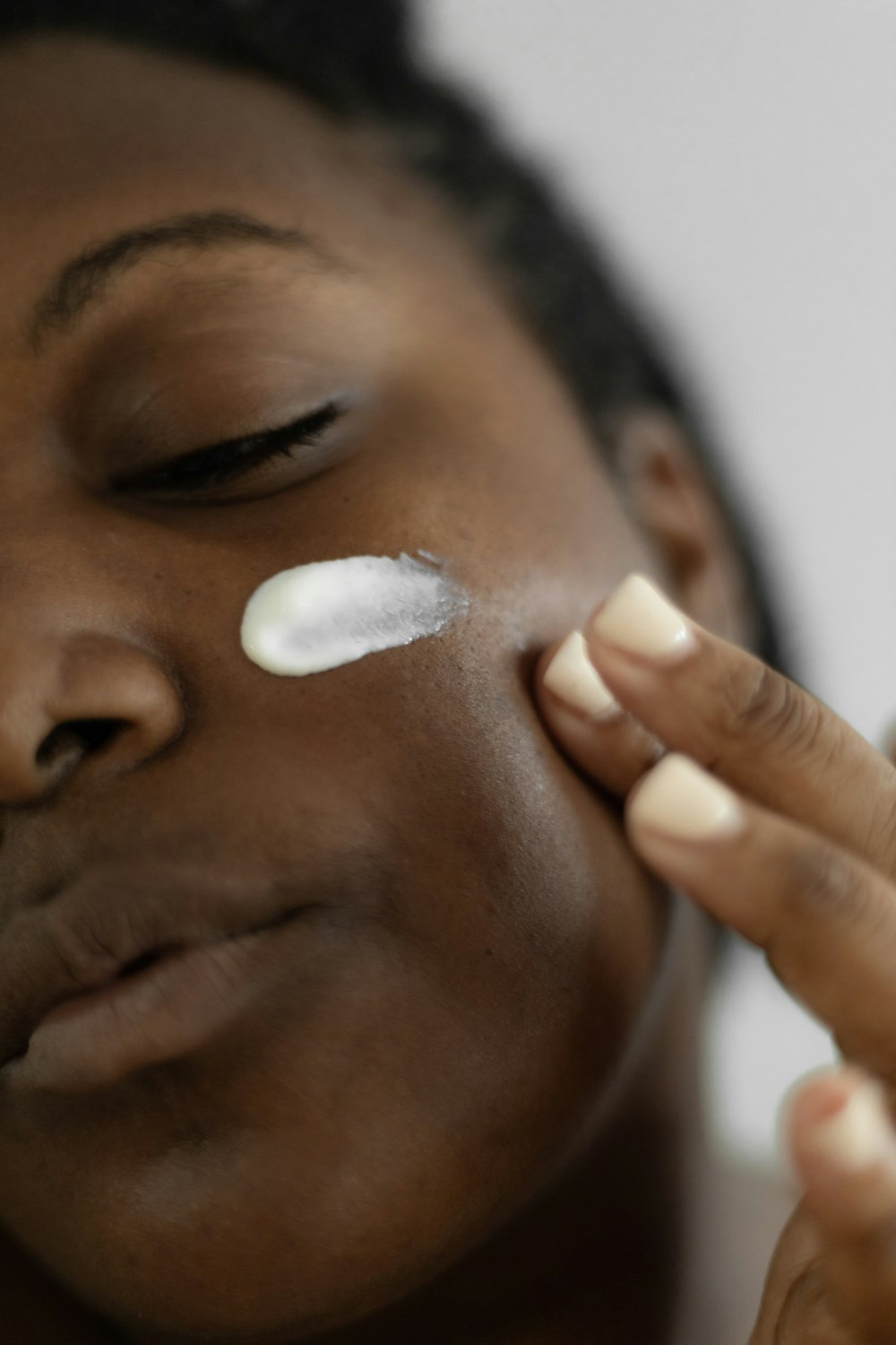 a woman is putting a lotion on her face