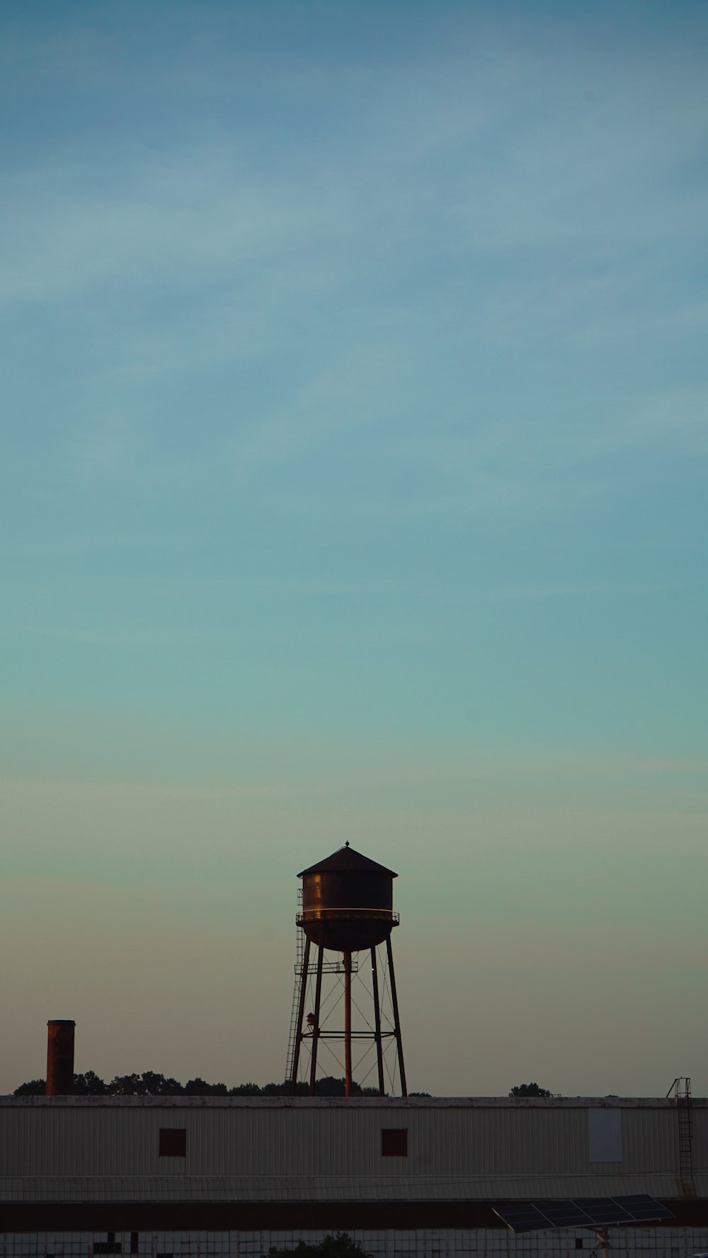 a water tower in the distance with a blue sky in the background