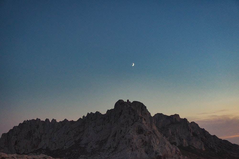 a mountain with a half moon in the sky