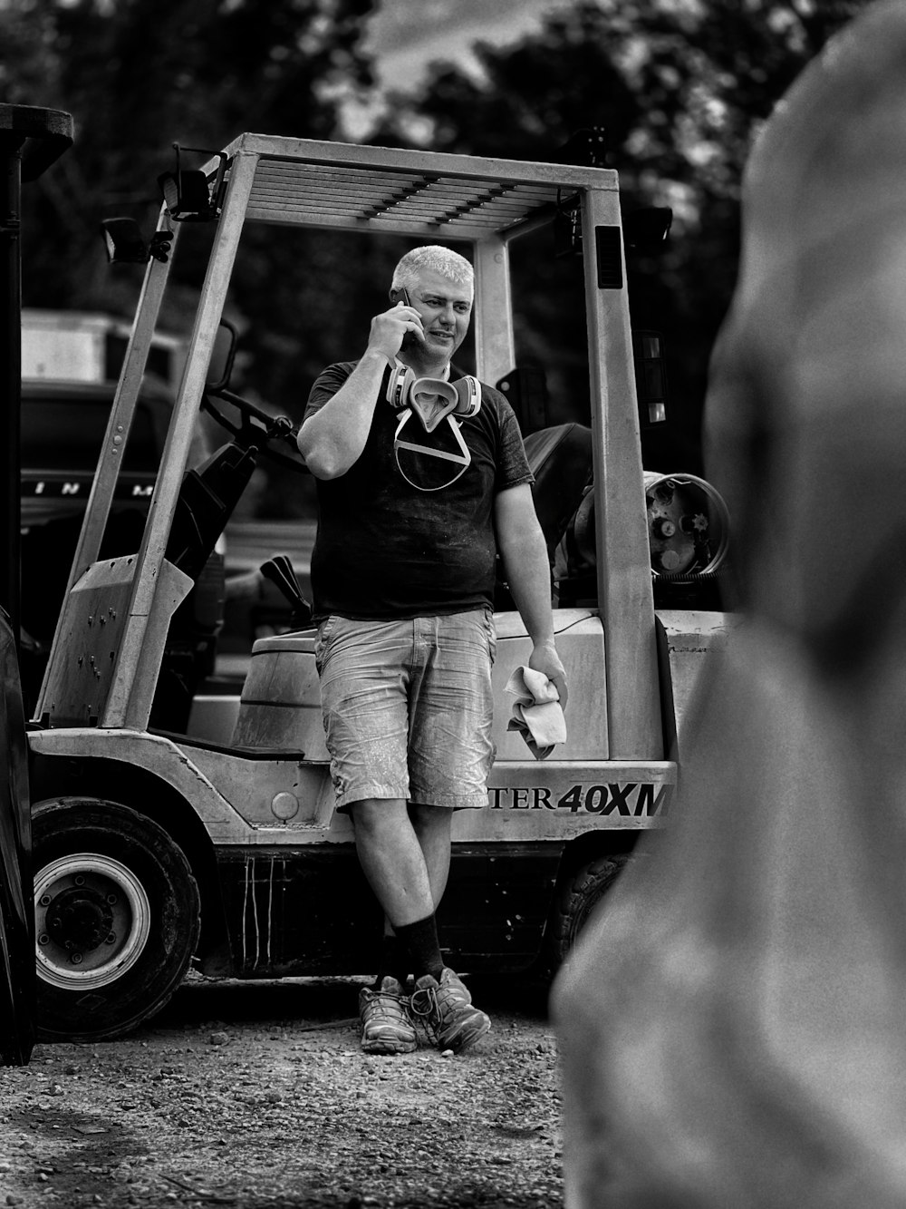 a man standing next to a forklift talking on a cell phone