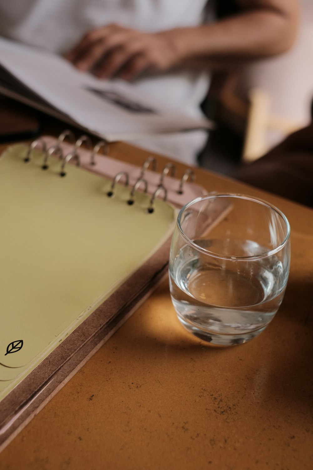 um copo de água sentado ao lado de um caderno