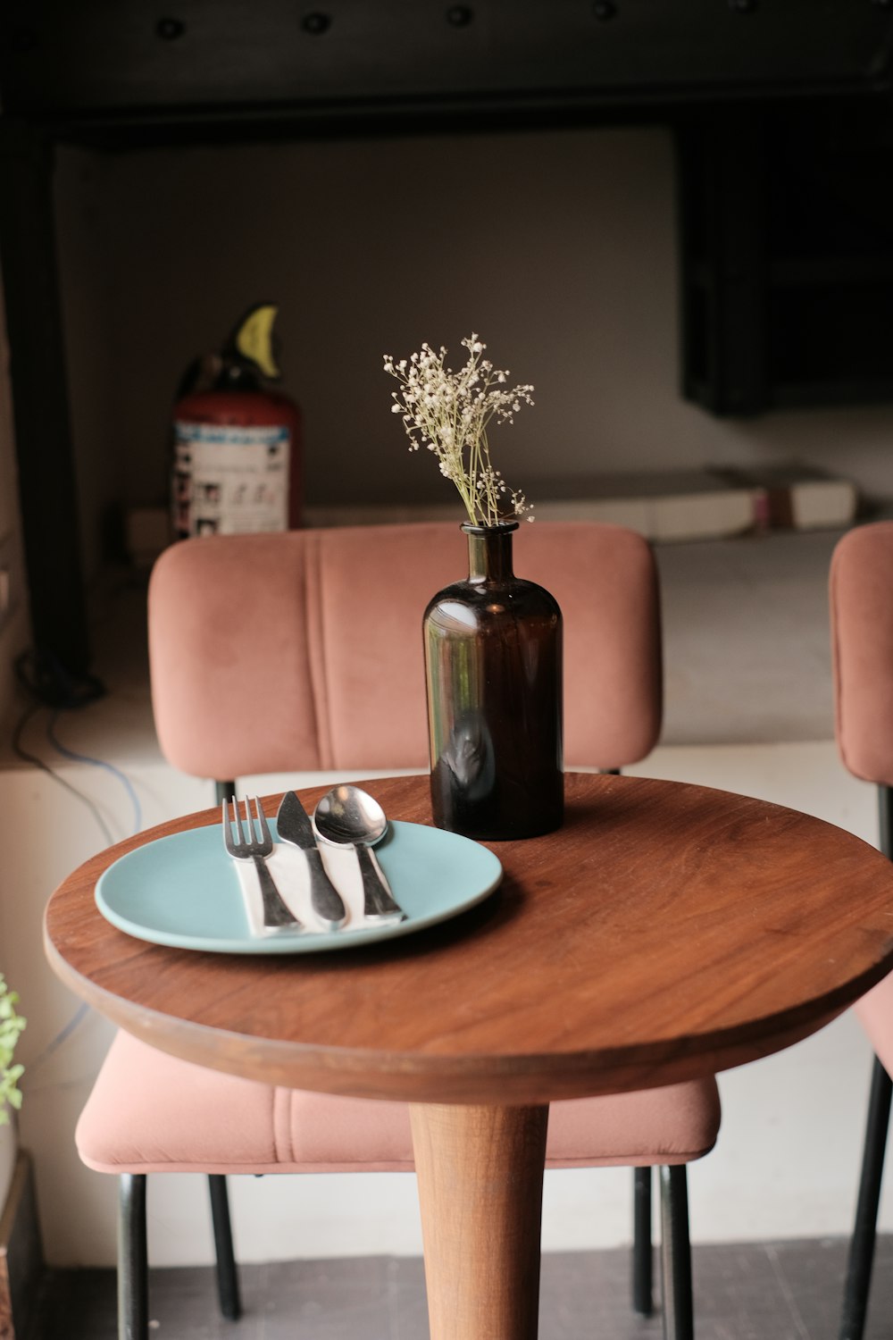 a wooden table topped with a blue plate and a vase filled with flowers