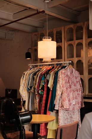 a room filled with lots of clothes and a lamp