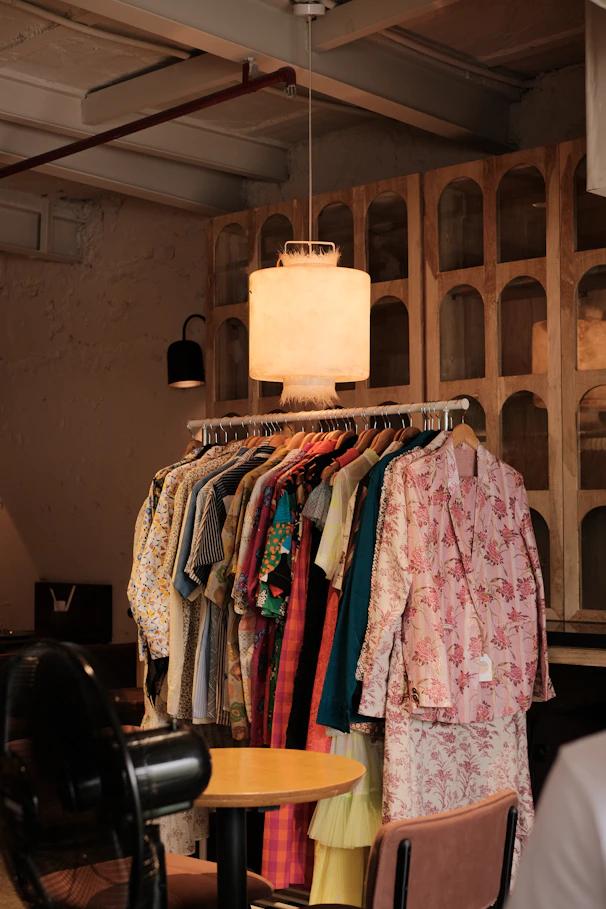 a room filled with lots of clothes and a lamp