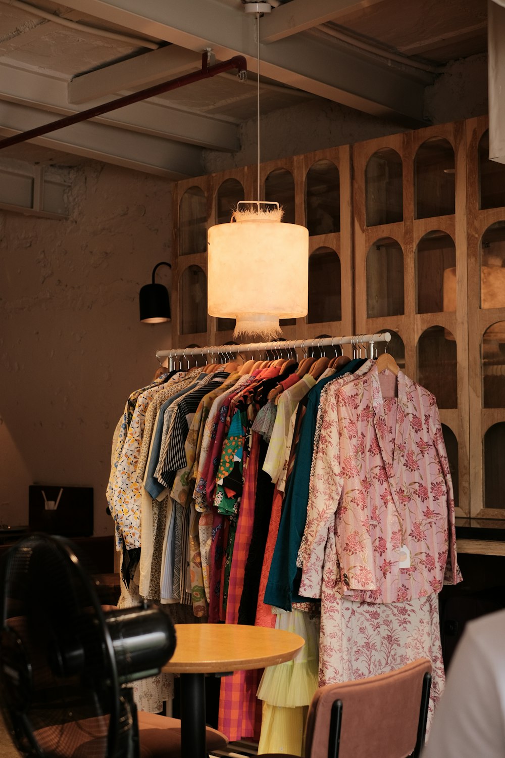 a room filled with lots of clothes and a lamp