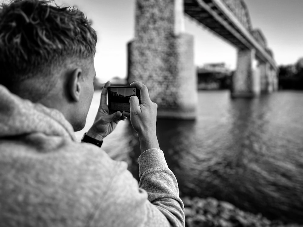 a man taking a picture of a bridge over water