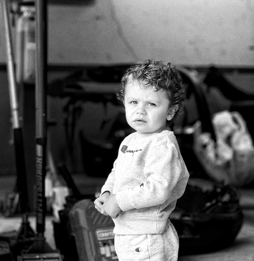 a young boy standing in front of a baseball bat