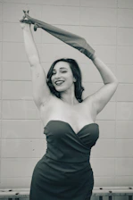 A warm, inviting photo of a woman smiling confidently, wearing elegant clothing that highlights her curves in golden and black tones.