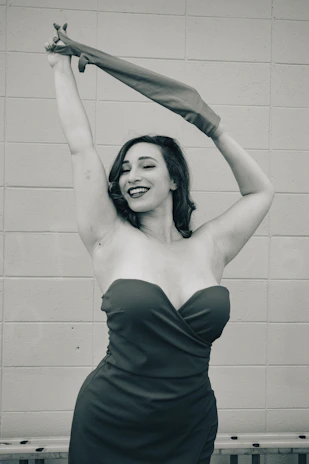 A warm, inviting photo of a woman smiling confidently, wearing elegant clothing that highlights her curves in golden and black tones.