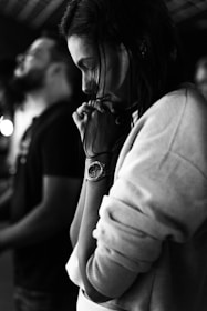 Woman with clasped hands, looking down in thought.