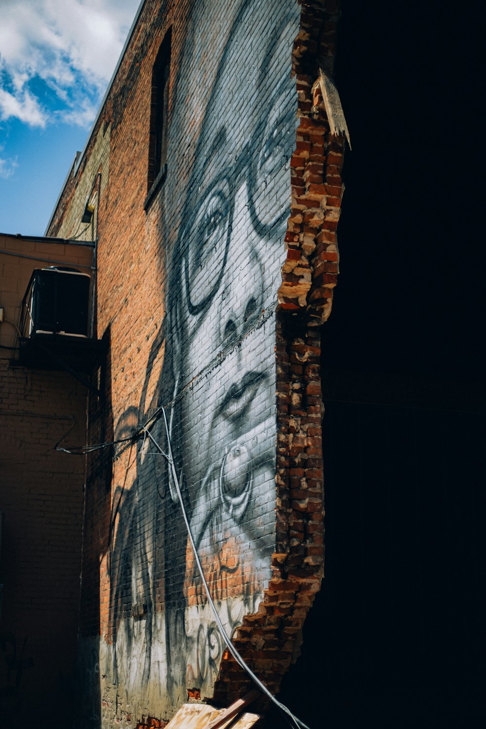 a brick wall with a painting of a man's face on it