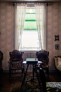 A warm, inviting parlor room with antique furnishings and soft natural light streaming through lace curtains.