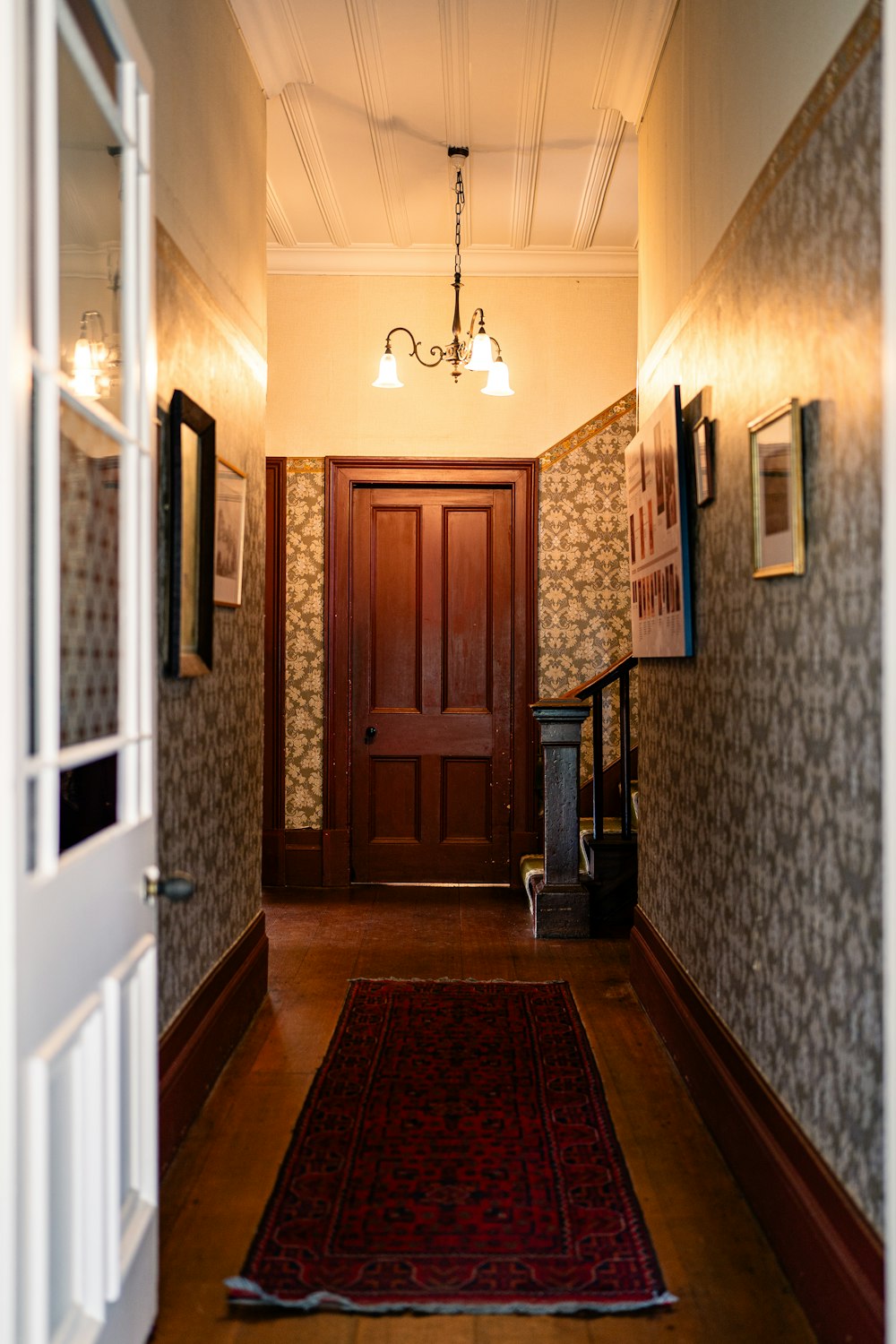 a hallway with a red rug and a wooden door