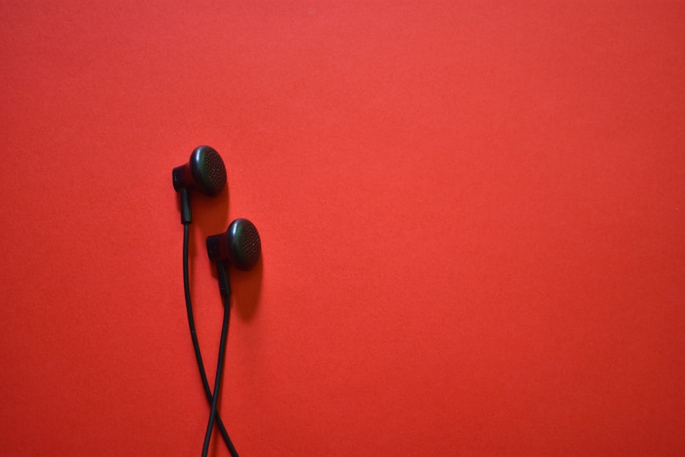 um par de fones de ouvido pretos em um fundo vermelho