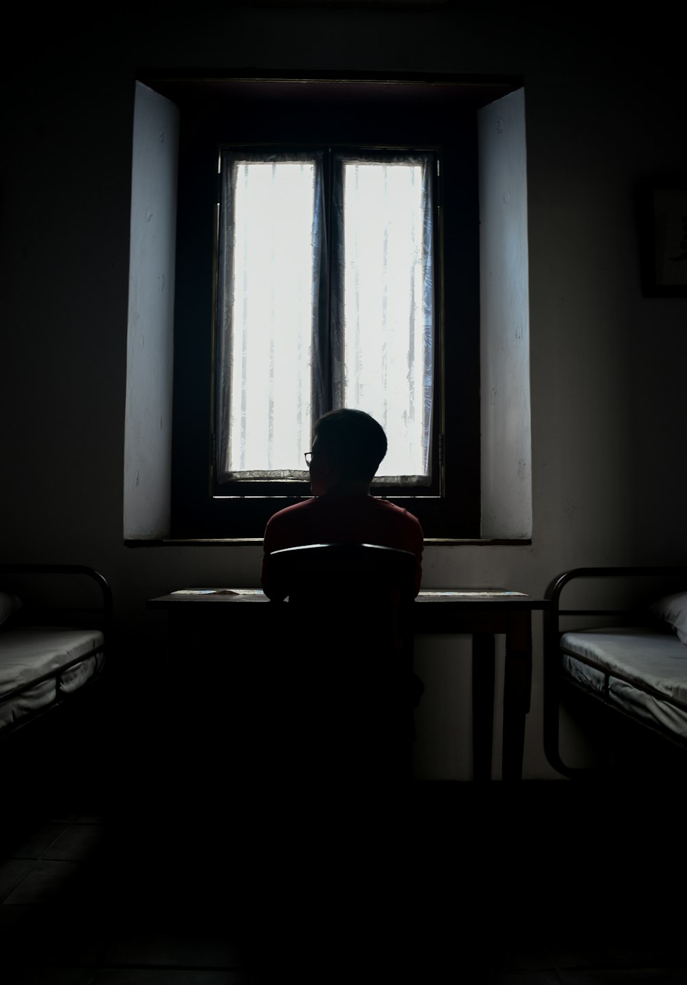a person sitting in front of a window in a dark room