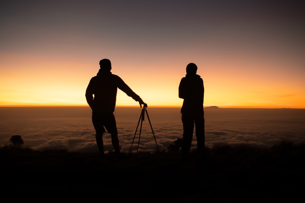 a couple of men standing on top of a mountain