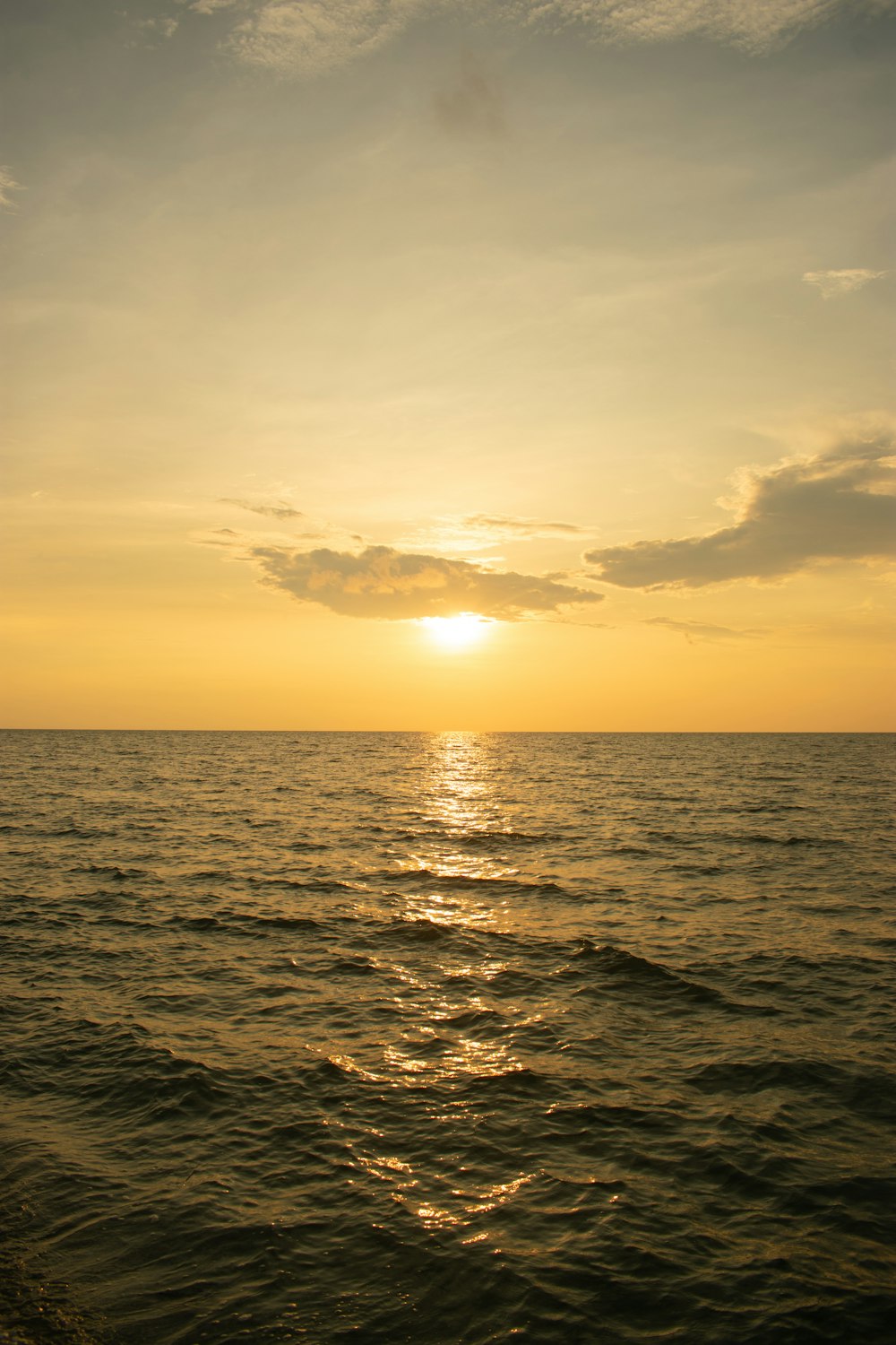 O sol está se pondo sobre o oceano em um dia nublado