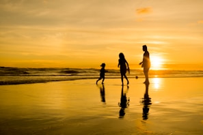 a family walking on the beach at sunset