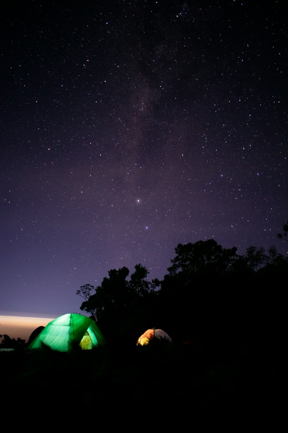 별이 가득한 밤하늘 아래 앉아 있는 두 개의 텐트