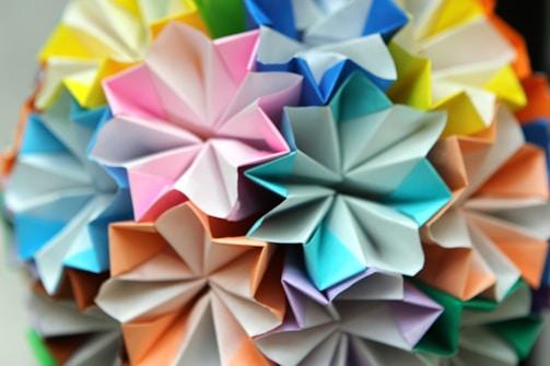 A vibrant arrangement of origami flowers with intricate folds, utilizing a spectrum of pastel and bright colors, creating a visually appealing and harmonious design.