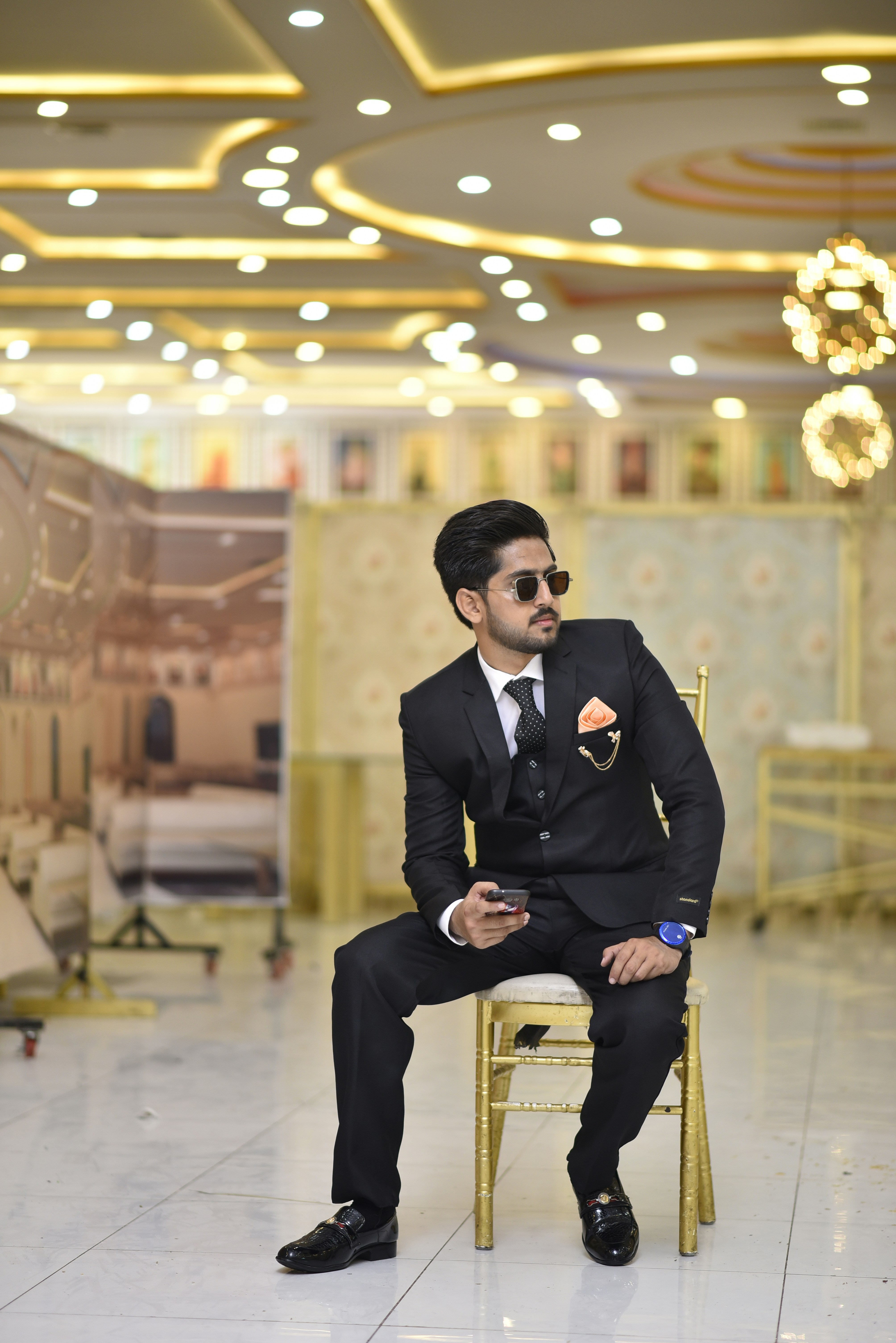 a man in a suit and sunglasses sitting on a chair