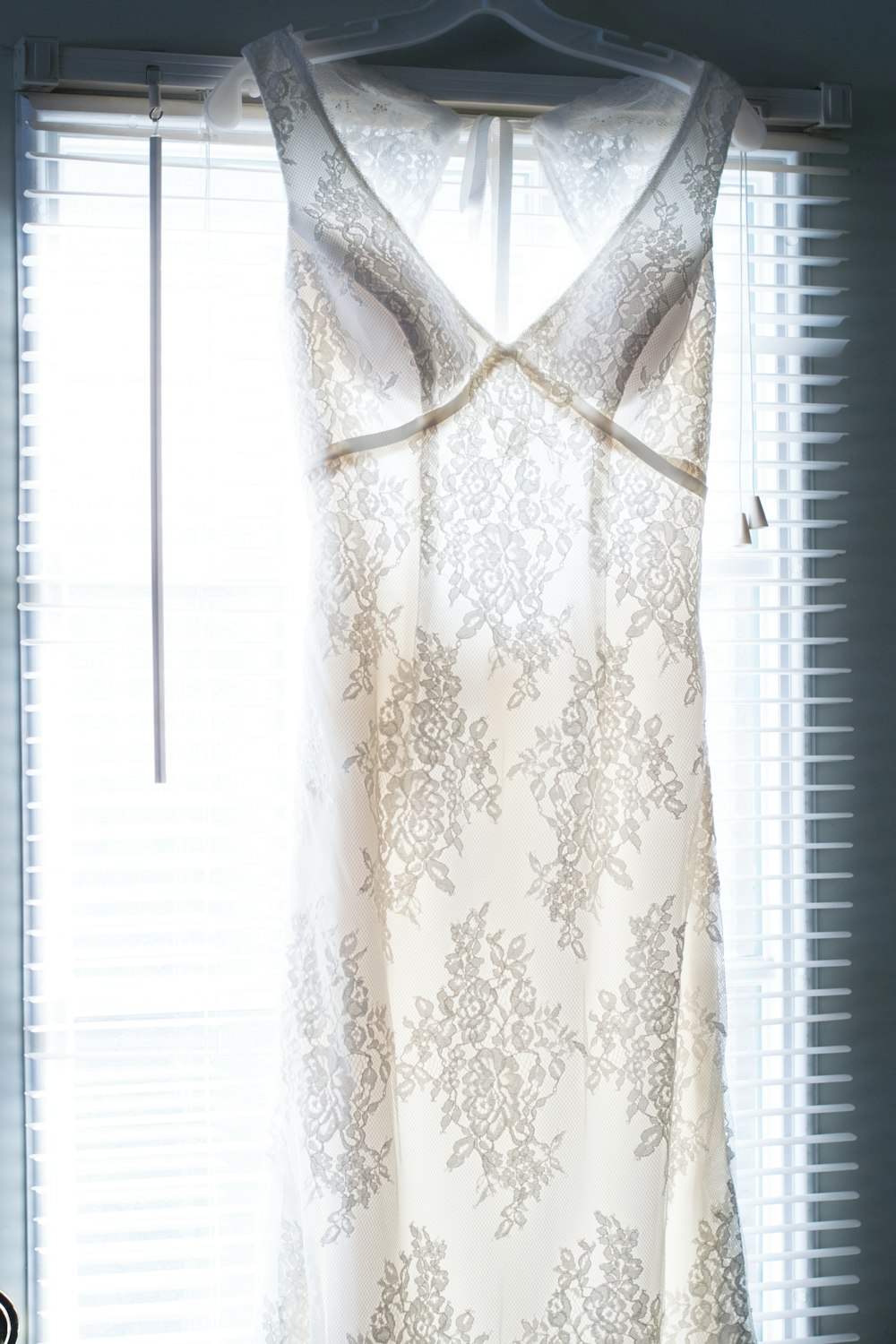 a white dress hanging up in front of a window