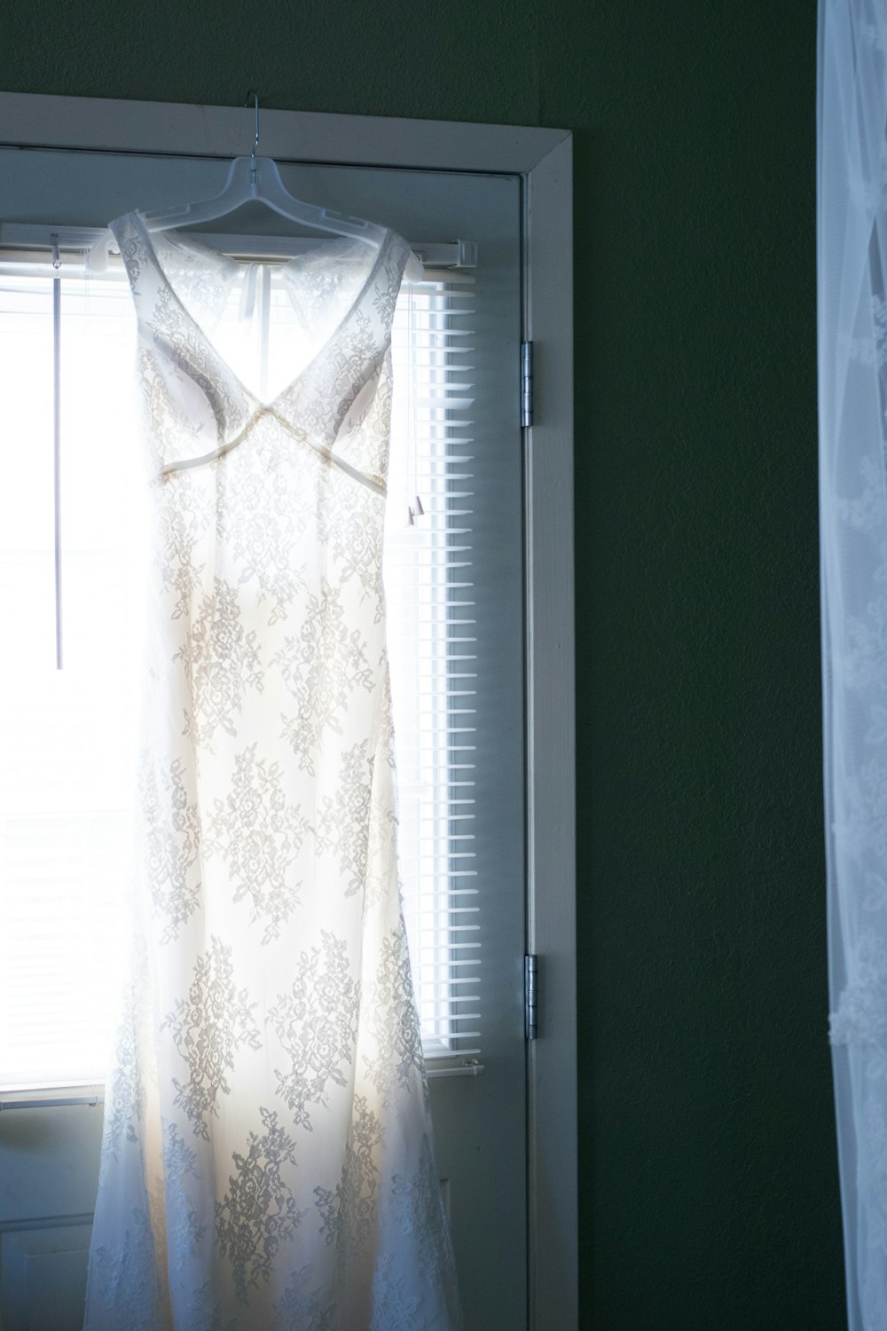 a white dress hanging in front of a window