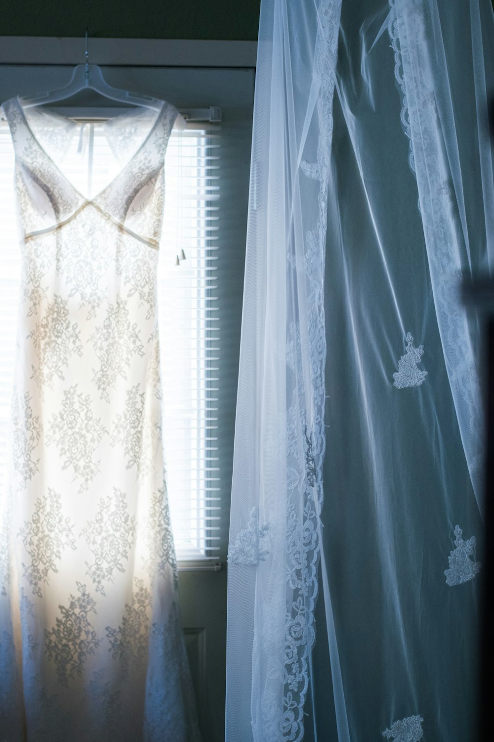 a white dress hanging in front of a window