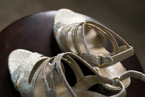 Elegant high-heeled sandals with metallic accents placed on a marble surface.