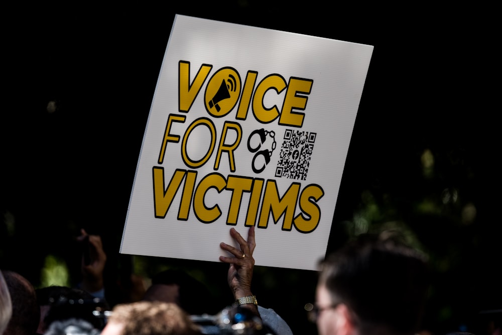 a person holding a sign that says voice for victims