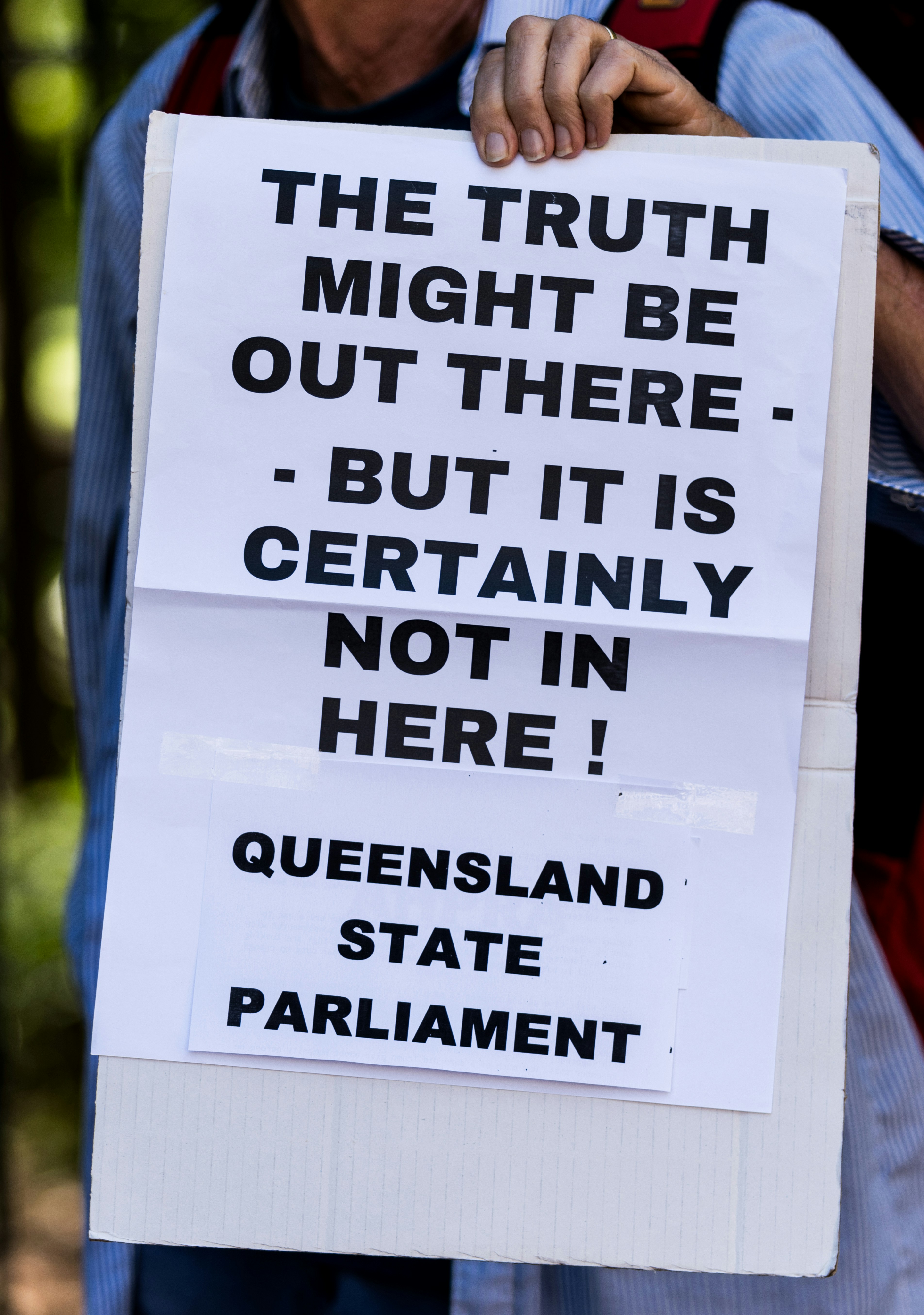 a man holding a sign that says the truth might be out there but it is