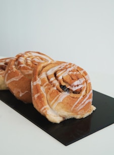 Close-up of a hand placing a fresh cinnamon roll into a paper bag on a wooden counter.