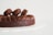 A decadent chocolate cake adorned with chocolate macarons on top. The cake is rich in texture, with smooth chocolate frosting arranged in decorative swirls. The surface of the macarons is glossy, indicating freshness. The background is minimalistic, enhancing the focus on the dessert.