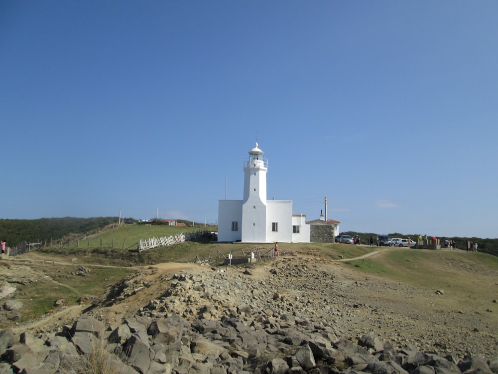 a white lighthouse sitting on top of a rocky hill