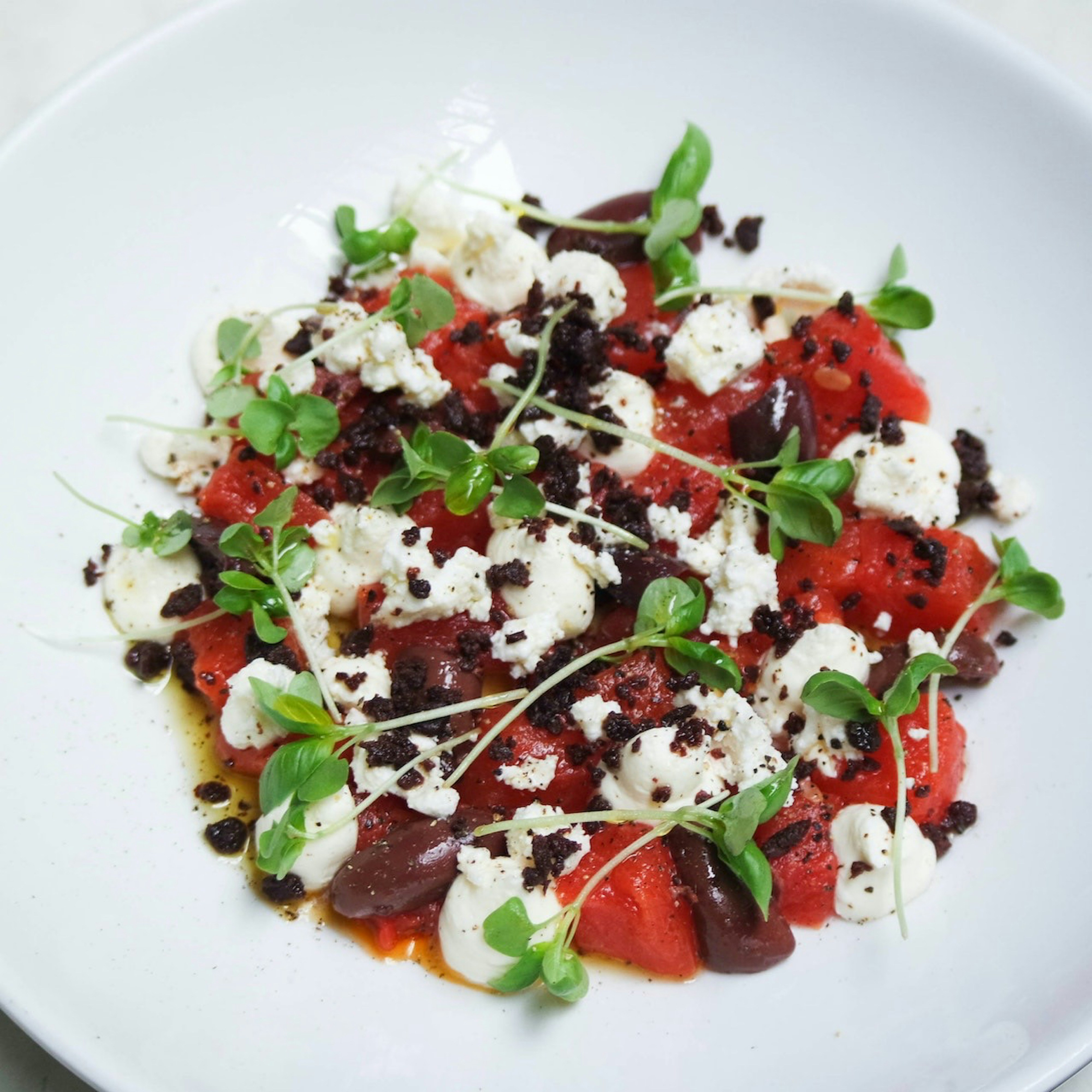 Fresh Greek watermelon feta salad with mint and olives on rustic wooden board