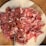 A wooden board with an assortment of cured meats including sliced salami, prosciutto, and other types of thinly sliced deli meats. The meats are arranged neatly on the board, showcasing a variety of red and pink hues with marbled fat.