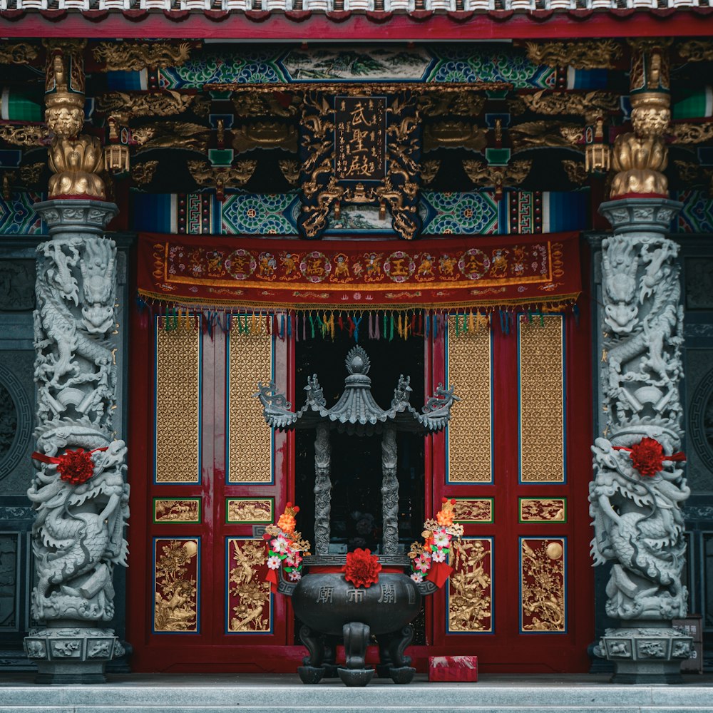 a red and gold building with a black vase in front of it