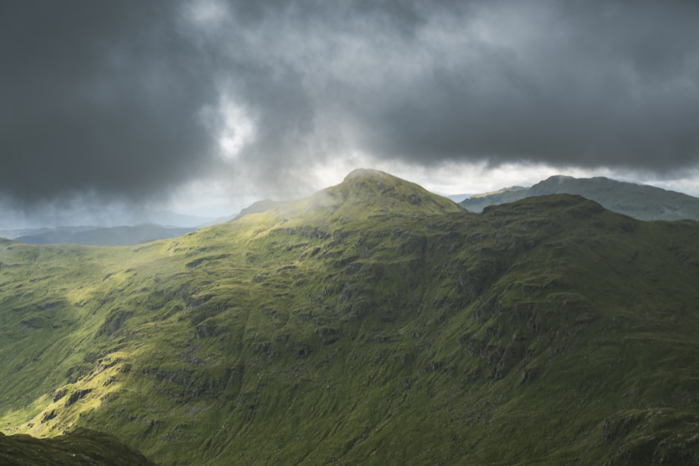 a green mountain range under a cloudy sky