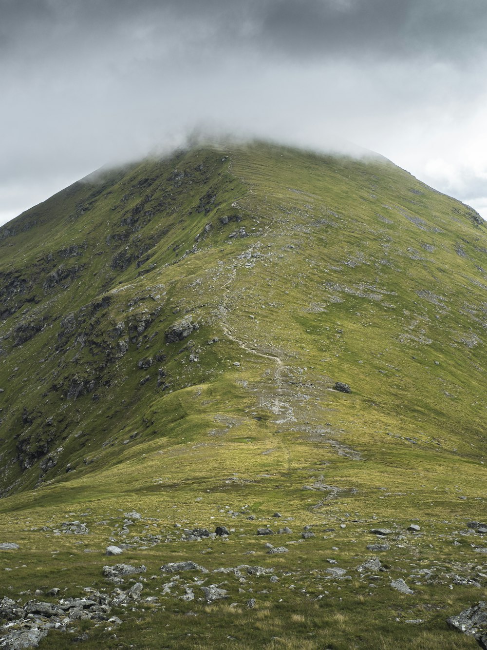 a very tall green mountain with a cloudy sky