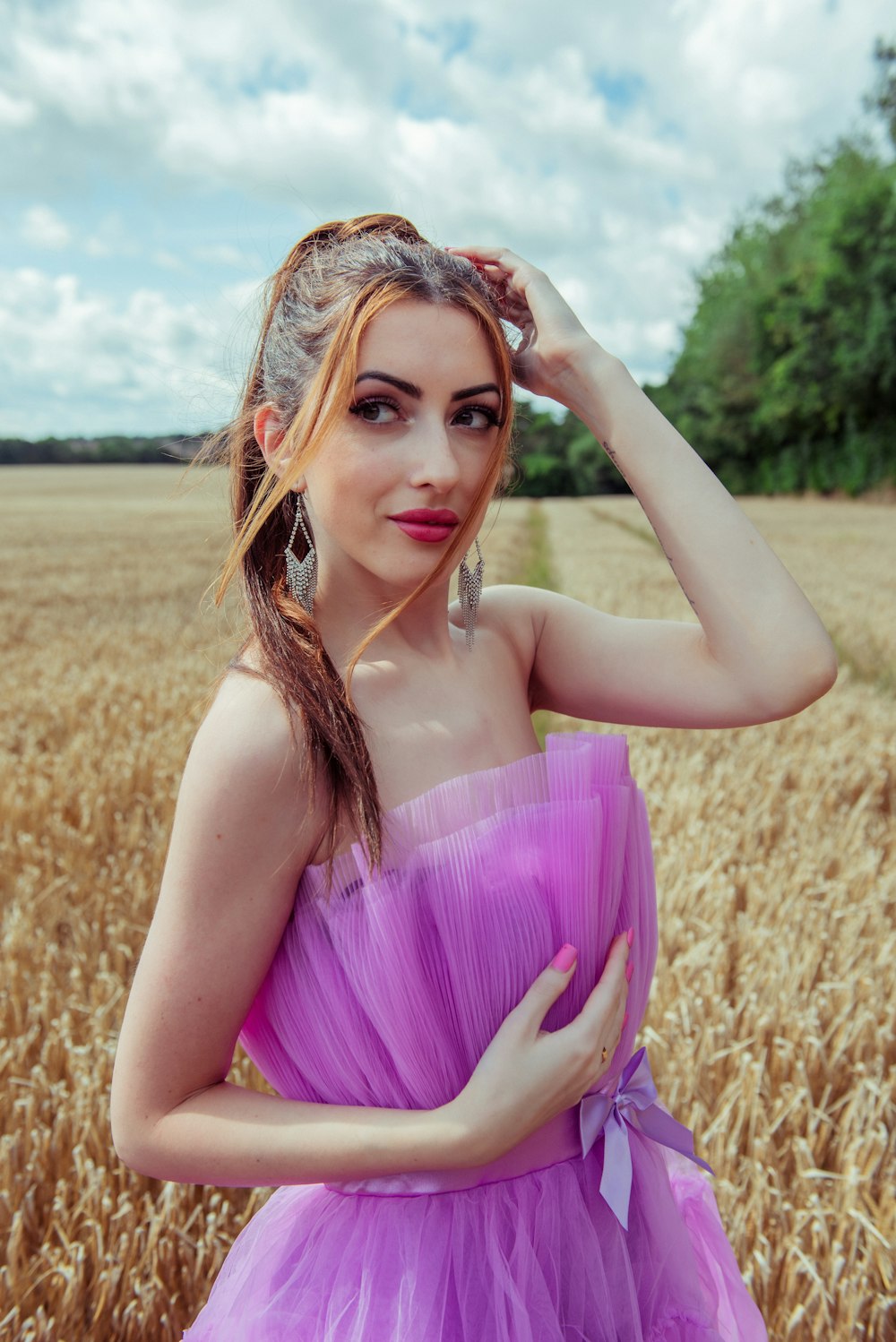 a woman in a purple dress standing in a wheat field