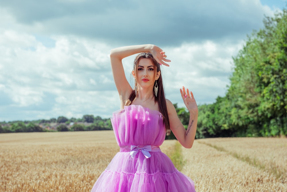 a woman in a purple dress standing in a field