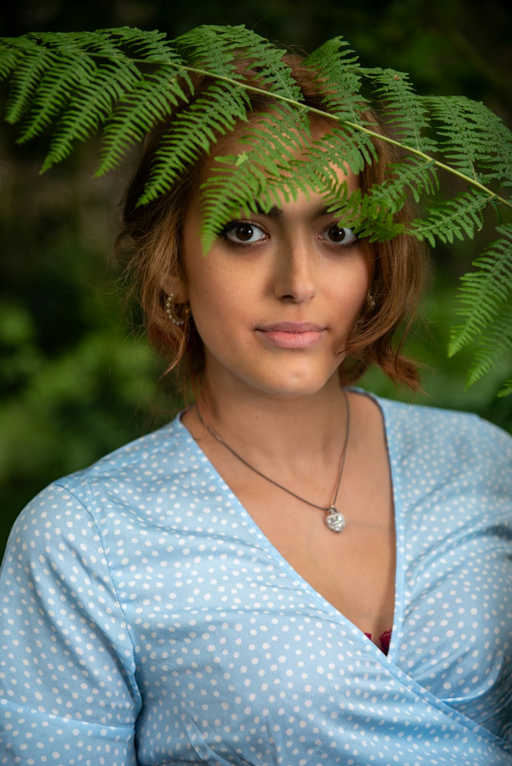 a woman wearing a blue shirt with a fern leaf on her head