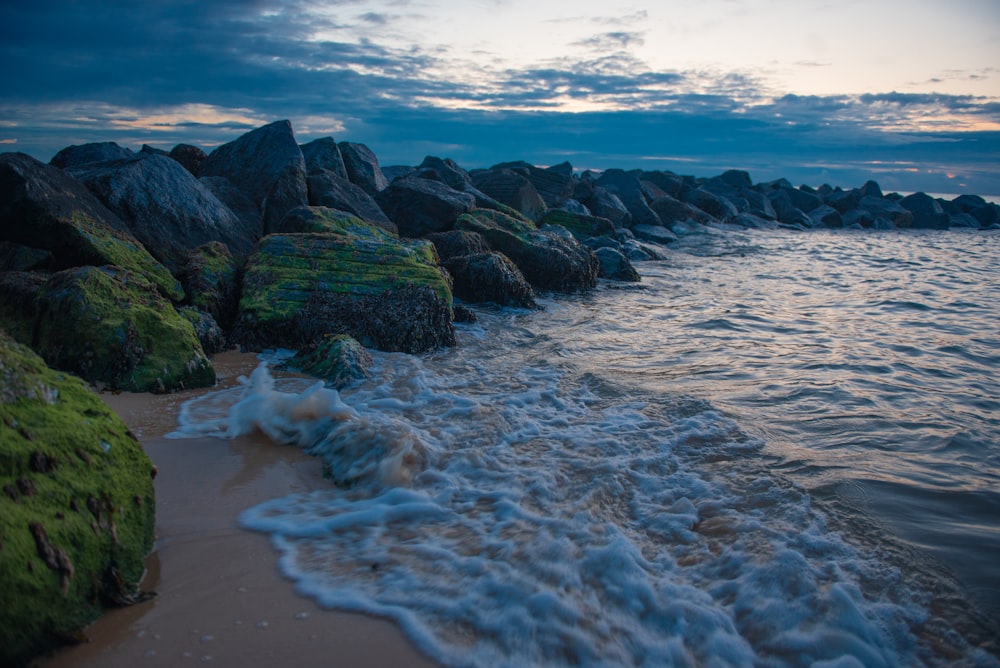 a beach with a bunch of rocks in the water