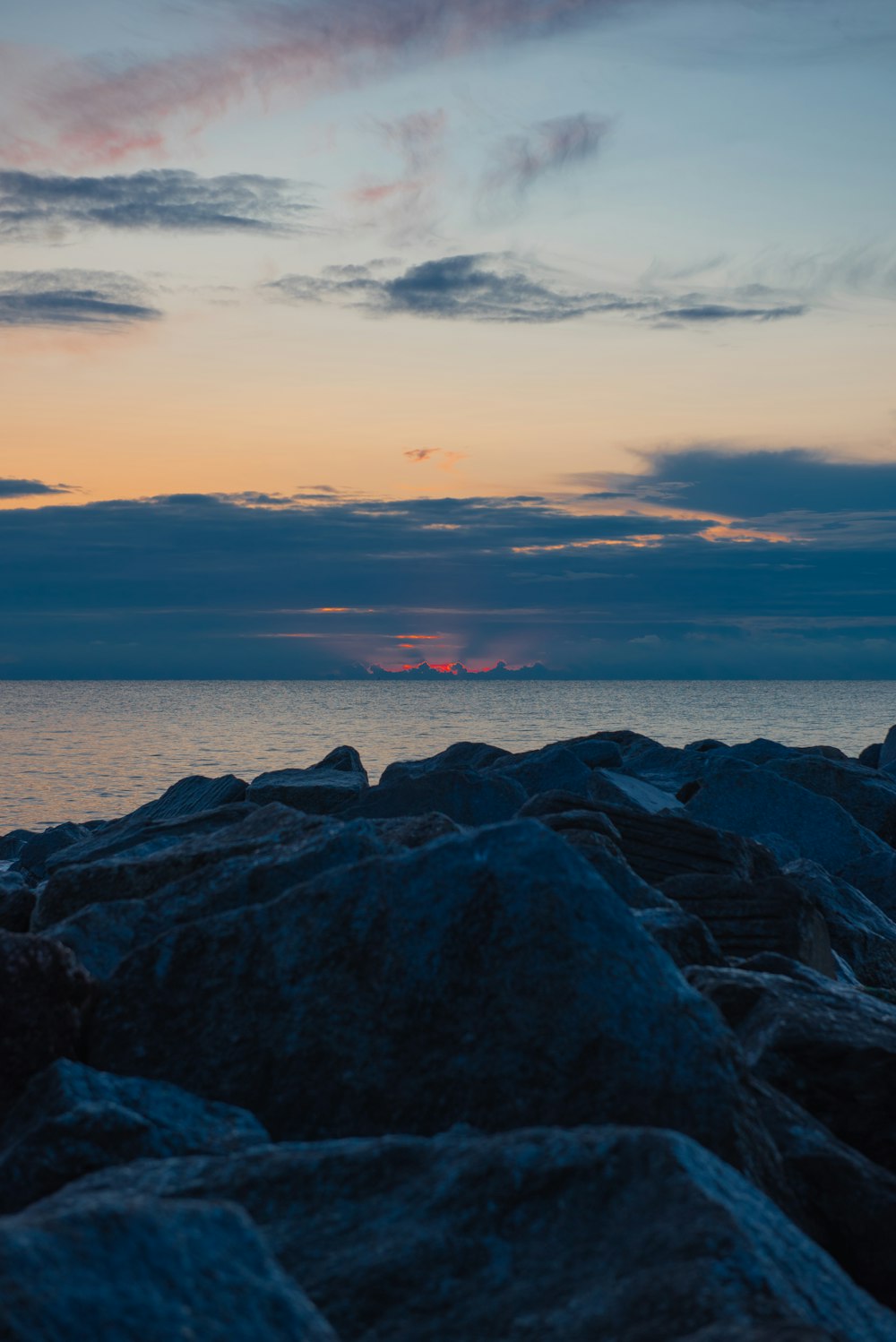 the sun is setting over the ocean and rocks