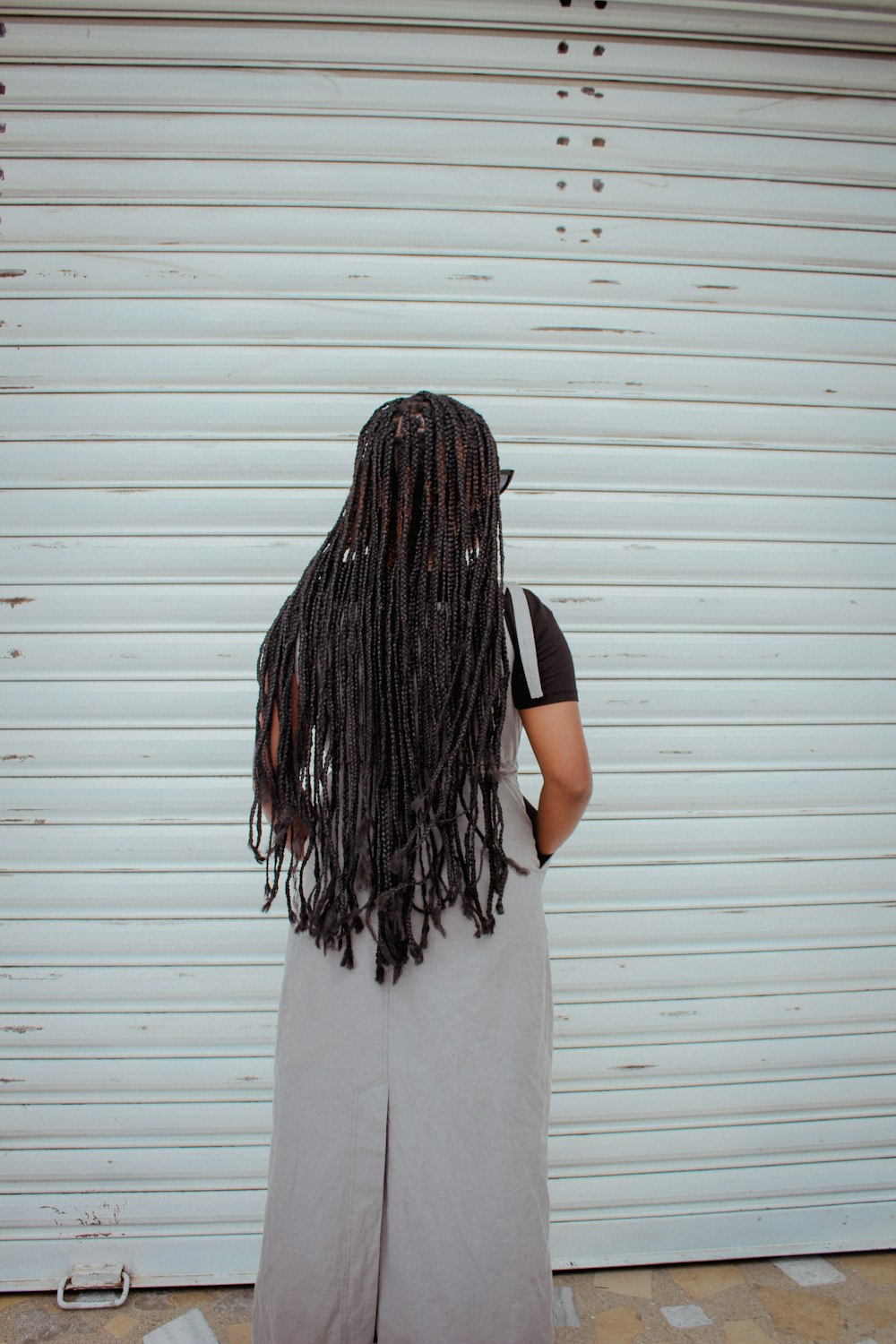 a woman with long dreadlocks standing in front of a garage door