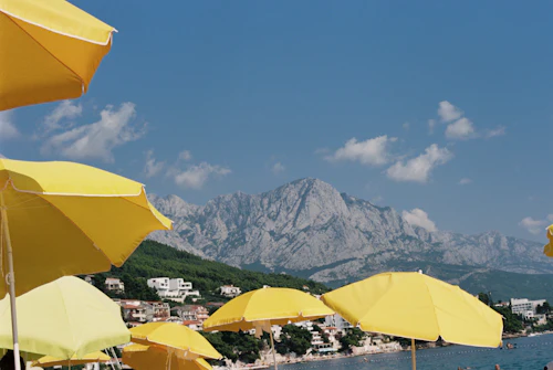 Parasols jaunes au premier plan, lac et montagne rocheuse au fond