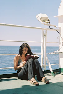 a woman sitting on a boat reading a book