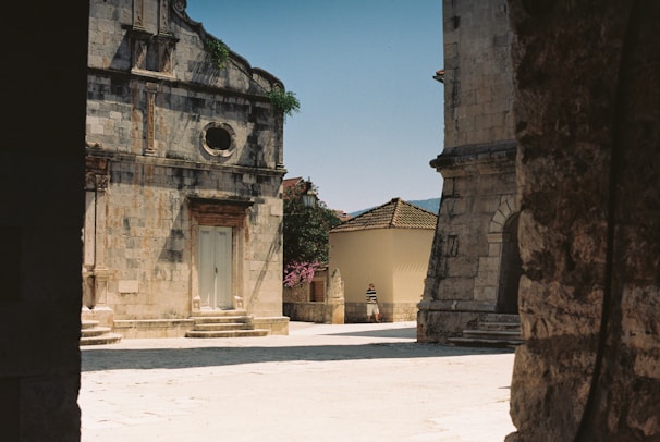 An empty, sunlit courtyard framed by old stone buildings, showing traces of past gatherings.