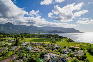 A panoramic view of the M3M SCDA residential towers surrounded by lush greenery and a 9-hole golf course under a clear blue sky.